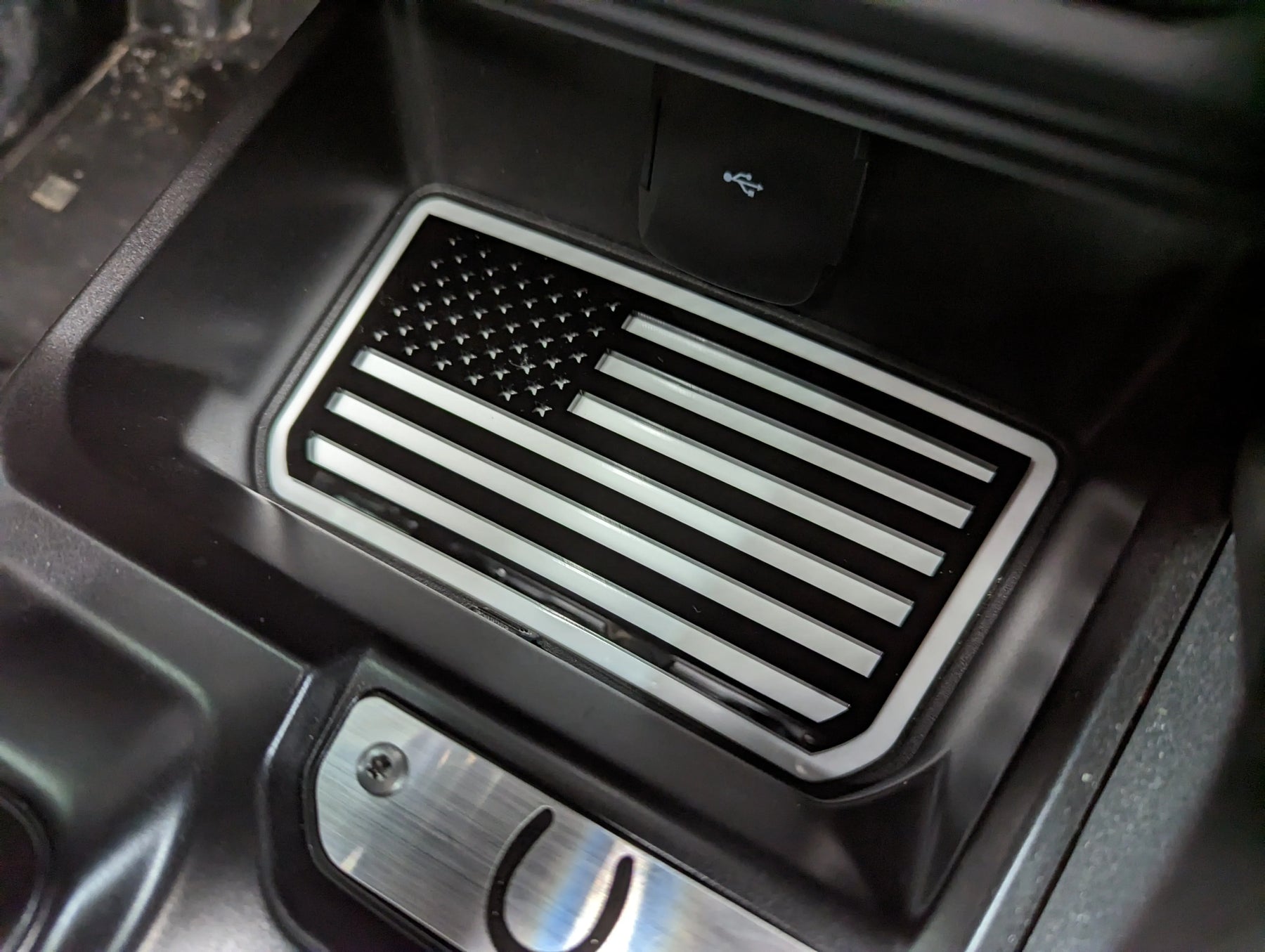 Bolsillo de almacenamiento de consola con emblema de bandera estadounidense. Compatible con Bronco® 2021+ (automático). Disponible en varios colores